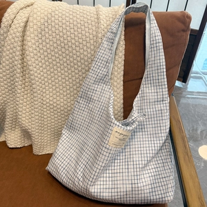 Gros plan d'un sac cabas à carreaux bleu et blanc avec écusson vintage sur un canapé