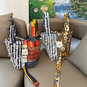 Bohemian patchwork denim tote bag with tassel edges and shoulder straps on a sofa