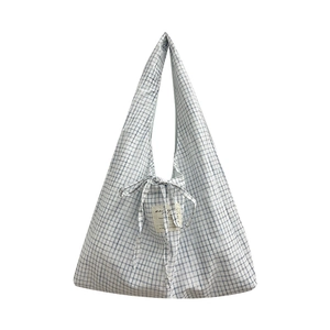 Sac cabas en toile à carreaux bleus avec fermeture à nœud et longues bandoulières sur blanc