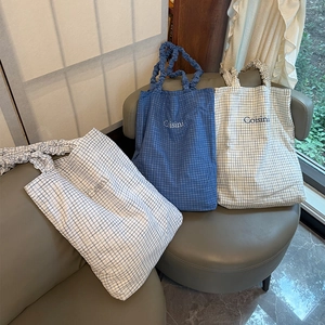 Close-up of checkered canvas tote bags with Coisini embroidery and ruffled straps