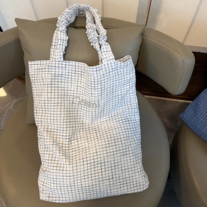 Detail of blue plaid tote bag featuring pleated cloud handles and Ceisini logo accent