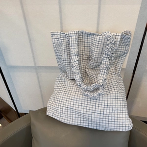 Detail of light blue checkered tote bag with ruffled shoulder strap and Cami embroidery