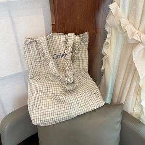 Minimalist summer plaid tote bag with blue embroidery and ruffled handles on a chair