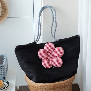 Close-up of black canvas lunch tote with plush red flower and nautical woven handles