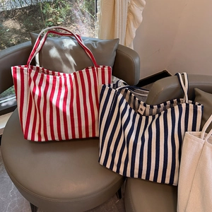 Detailed close-up of striped canvas tote bags with magnetic snaps in three colors