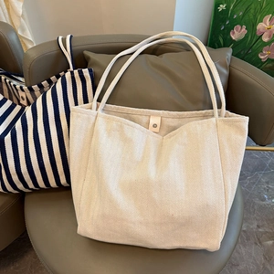 Detail of herringbone and striped large canvas tote bags on a modern grey chair