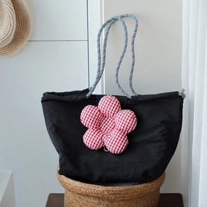 Detail of black canvas lunch tote bag with checkered 3D flower and rope handle