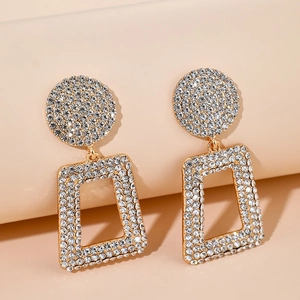 Close-up of geometric gold-plated earrings with pavé crystals and sparkling rhinestones