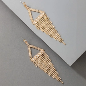 Detail of long gold tassel earrings with geometric triangle and crystal fringe