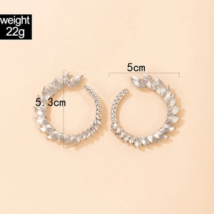 Macro detail of geometric leaf-shaped silver earrings with size and weight dimensions