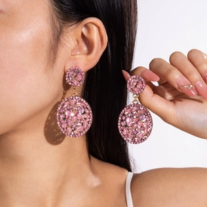 Detailed view of pink crystal geometric drop earrings on model with gold metal plating
