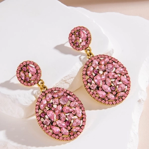 Detailed macro of vintage gold earrings with pink crystals and intricate geometric studs