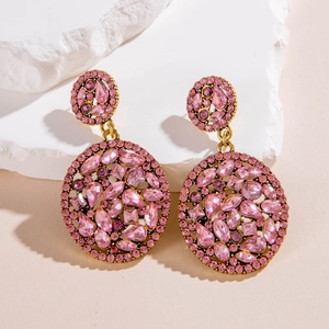 Macro shot of luxury gold geometric earrings with pink crystals on white stones