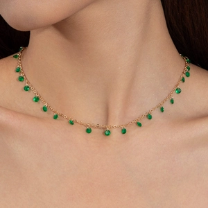 Gold choker necklace featuring multiple round green faceted stones worn by a model