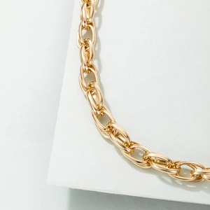 Detailed close-up of a chunky golden hip hop chain link necklace on a display card