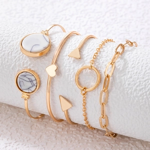 Detail of five-piece gold bracelet set with marble inlay and geometric heart charms