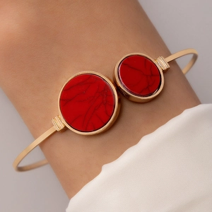 Close-up of golden open bangle featuring round red faux stone with marble texture