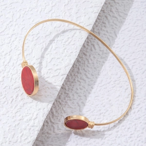 Detail of matte gold open cuff bracelet with oval reddish-brown faux stone inlays