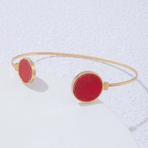 Macro shot of gold C-shaped open cuff bracelet featuring large round red marble stones