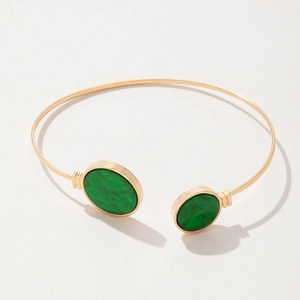 Close-up of gold open cuff bracelet featuring green marble resin stone round ends