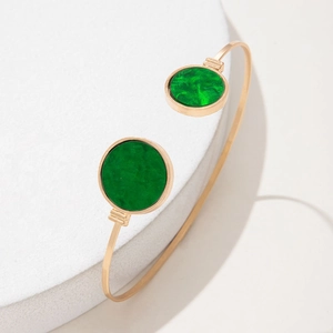 Detailed shot of a gold open cuff bracelet with circular green marble-textured resin inlays