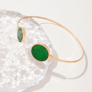 Detail of a gold open bangle featuring green faux gemstone marble texture inlay