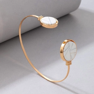 Detail view of a gold-plated C-shaped cuff bracelet with marble texture resin inlays
