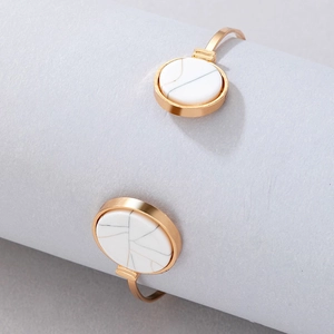 Detail of gold-plated open cuff bracelet with white marble stone inlay on a display