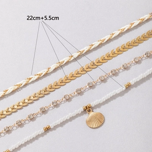 Detail of four-piece layered anklet set with beads, gold leaves, and shell pendant