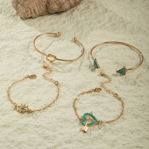 Detail view of a 4-piece gold bohemian bracelet set with turquoise stones and charms