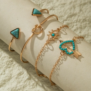 Detail of 4pcs gold jewelry set with turquoise triangles, evil eye and heart arrow bracelet