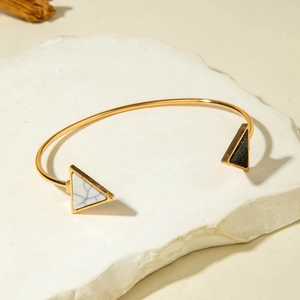 Detail of geometric open cuff featuring black and white marble triangles in gold finish