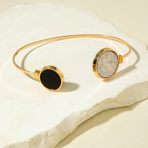 Detailed macro view of an open gold bangle with black and white marble geometric circular inlays