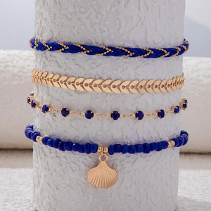Primer plano de conjunto de tobilleras bohemias con cuentas azules y concha dorada
