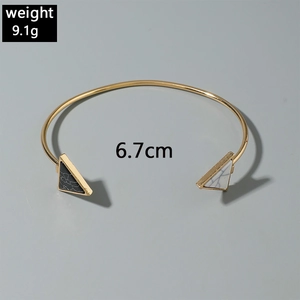 Detailed view of an open gold bangle with black and white triangular faux marble stones