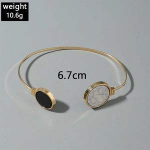 Detail of gold open bracelet with black and marble inlay showing 6.7cm diameter