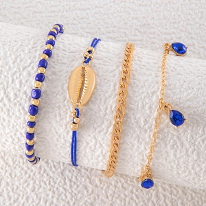 Detalle de un set de cuatro tobilleras doradas y azules con conchas y cristales