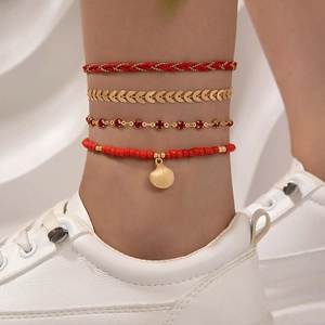 Detalle de set de tobilleras bohemias rojas con colgante de concha y cadena dorada