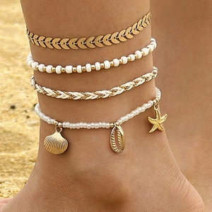 Detalle de conjunto de cuatro tobilleras bohemias con conchas y estrellas de mar en la arena