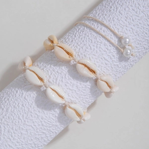 Detailed close-up of shell bead jewelry on a textured stand for beach vacations