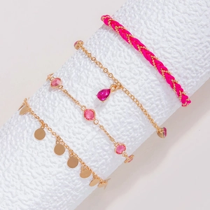 Detalle de set de cuatro tobilleras doradas con piedras rosas y cordones trenzados