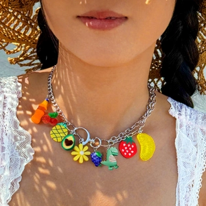 Detail of chunky silver chain necklace with colorful Y2K fruit and dinosaur charms