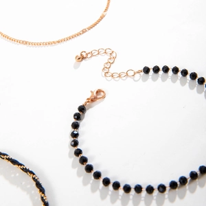Macro detail of multi-layer beaded anklets set featuring red beads and cherry pendants