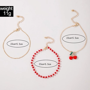 Three-piece gold anklet set with red beads and sparkling cherry pendant detail