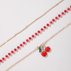 Detailed view of triple-layer gold anklet set with red beads and rhinestone cherry charms