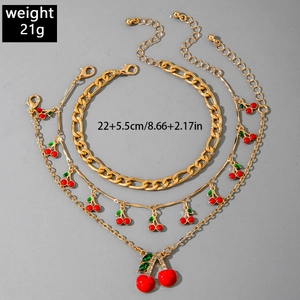 Detailed view of triple-layered gold anklet set with red cherry pendants and sizing specs