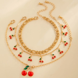 Detailed view of gold triple layered anklet featuring red enamel cherry charms and rhinestones