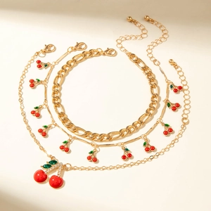 Macro detail of gold cherry jewelry set with red enamel fruits and sparkling crystal leaves