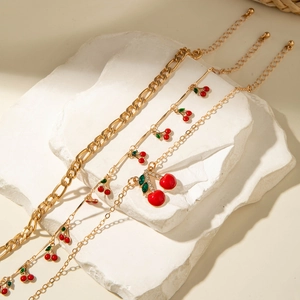 Close-up of red cherry charms and crystal details on gold layered anklet set