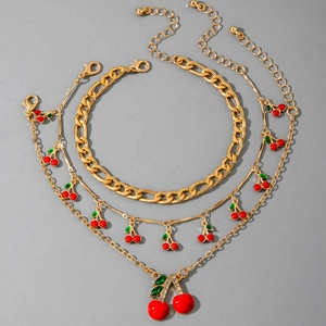 Detailed view of 3-piece gold chain set featuring red cherry charms and crystal leaves